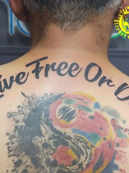A bold statement piece on the back: "Live Free Or Die." The script is strong and clear, placed above an existing colorful tattoo.
