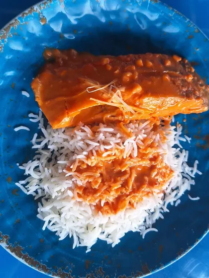 A plate of Goan fish curry with rice, an authentic and flavorful dish enjoyed with a view of the sea.