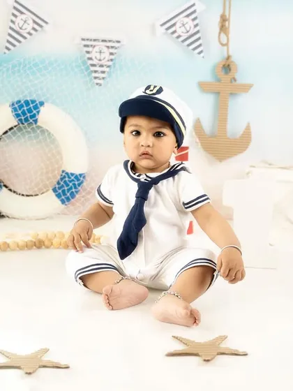 A classic pose in a full sailor outfit. The backdrop of the sea and the various props complete the charming nautical scene.