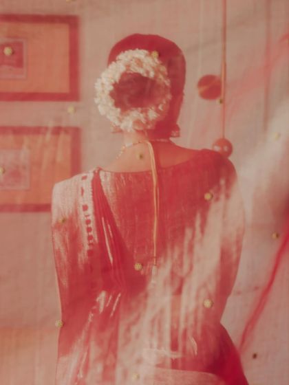 An artistic portrait of the bride, seen through her red veil. The soft focus and dreamy quality of the image capture the feeling of a memory, a gentle glimpse of the bride before she steps into her new life.