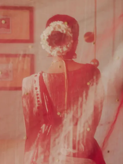An artistic portrait of the bride, seen through her red veil. The soft focus and dreamy quality of the image capture the feeling of a memory, a gentle glimpse of the bride before she steps into her new life.