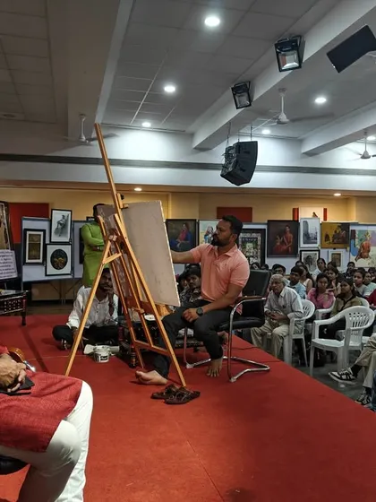 A wide view of the stage during my watercolour portrait demonstration at Nashik Kala Niketan. The setup is simple: a model, an easel, and a live audience.