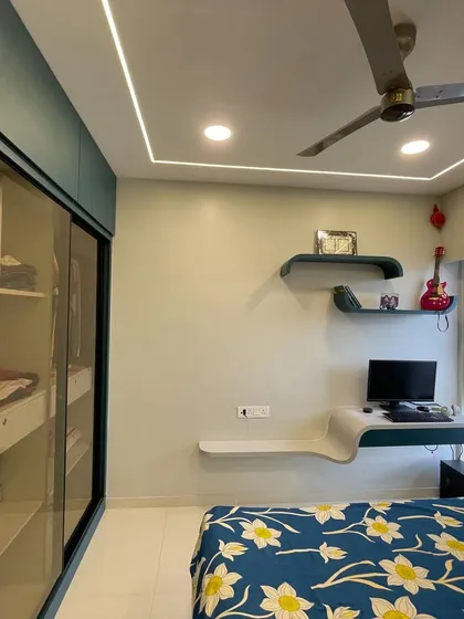 The room includes a compact study desk with curved shelves and a well-organized wardrobe with glass doors, making it perfect for a growing child.