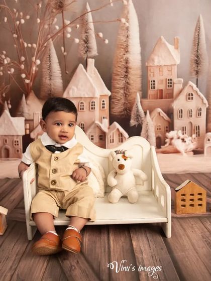 A winter wonderland in the studio. This little boy is dressed smartly for a visit to a magical, snowy village, complete with miniature houses and a teddy bear friend.
