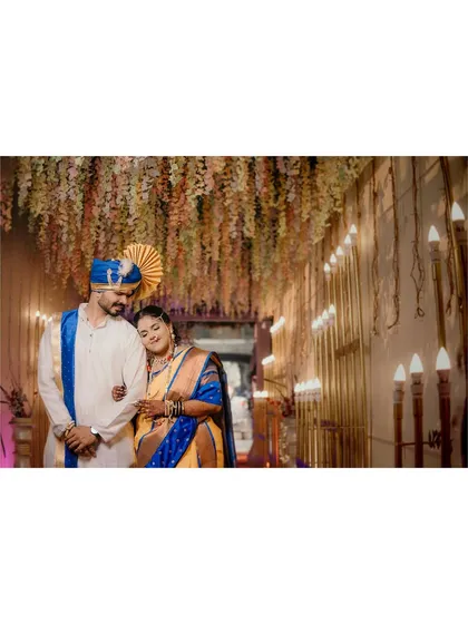 A wide shot showing the couple in a beautifully decorated wedding hall. The hanging floral arrangements and warm lighting create a magical atmosphere for their special day.