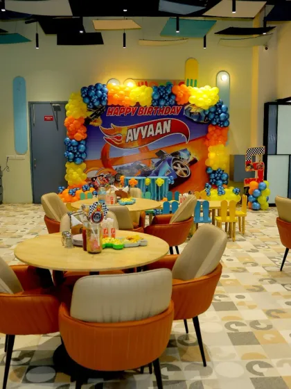 The Hot Wheels theme extends to the dining area, with a large backdrop and coordinated balloons creating an immersive party environment.