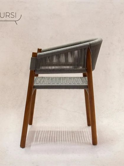 A side profile of the 'Tali' chair, showing its modern silhouette. The combination of the warm teak wood and cool grey rope is a contemporary favorite.