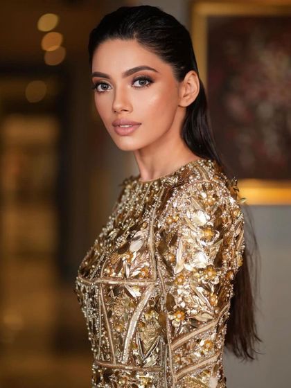 A close-up of the wet-look glam. The makeup is clean and minimal, with a focus on a flawless base and a natural lip, allowing the high-fashion styling to shine.