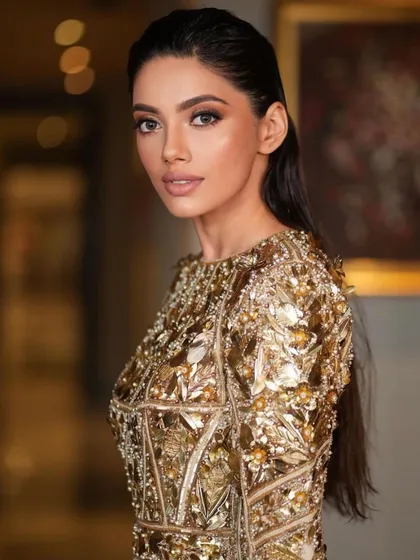 A close-up of the wet-look glam. The makeup is clean and minimal, with a focus on a flawless base and a natural lip, allowing the high-fashion styling to shine.