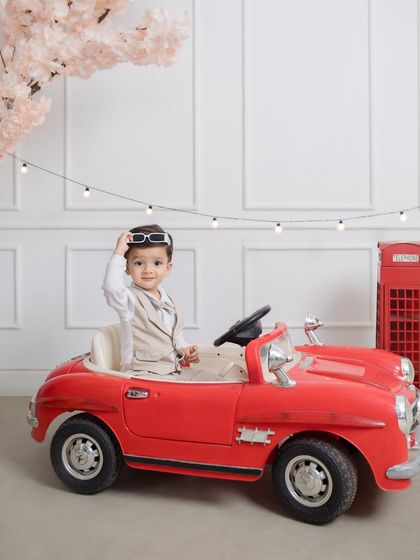 The epitome of cool, this little guy lifts his sunglasses for a suave birthday portrait in his red convertible.