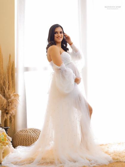 A full-length shot of the mother-to-be in a stunning white gown. The bright, airy feel of our Boho setup makes it perfect for these angelic portraits.