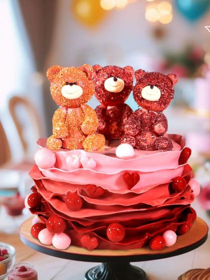 An adorable cake with three sparkling red teddy bears sitting on a bed of red ruffles. This cute and cuddly design is full of love and perfect for a special celebration.