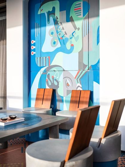 The 'Embrace' mural seen here as a backdrop for a modern dining setup, demonstrating how our large-scale art can define and elevate a functional space.