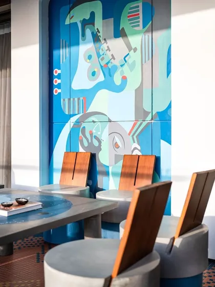 The 'Embrace' mural seen here as a backdrop for a modern dining setup, demonstrating how our large-scale art can define and elevate a functional space.