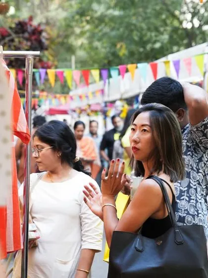 Visitors browsing through a stall, captivated by the variety of handmade clothing and textiles on display.
