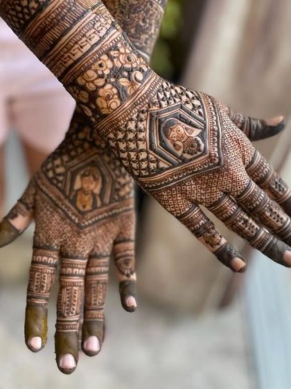 A close-up of the intricate details in a bridal mehendi. This design features a bride portrait and a Ganesh figure, surrounded by fine lines and traditional patterns.