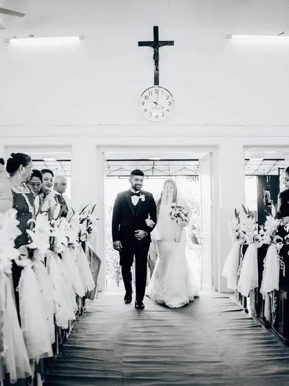A wider perspective of the wedding processional, capturing the guests and the solemnity of the moment in black and white.