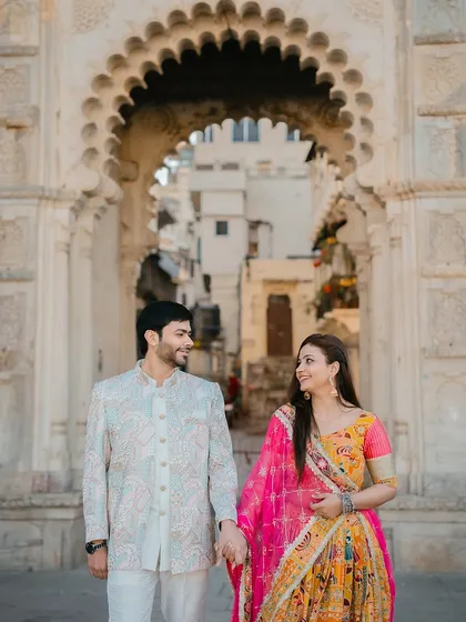 A candid shot of the couple walking hand-in-hand through an arched gateway in Udaipur, creating a sense of journey and togetherness.