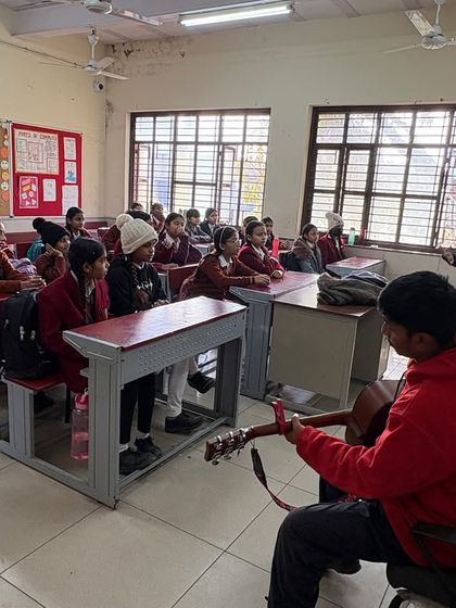 A student plays the guitar for his classmates while an instructor guides the session. We empower students to take on leadership roles and share their skills with their peers.