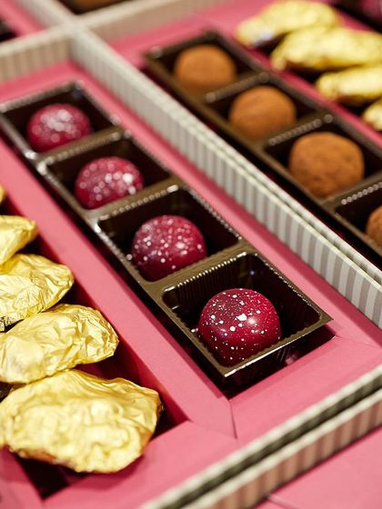 A close-up of the contents of a corporate gift box, featuring our assorted Belgian truffles and gold-wrapped almond rochers.