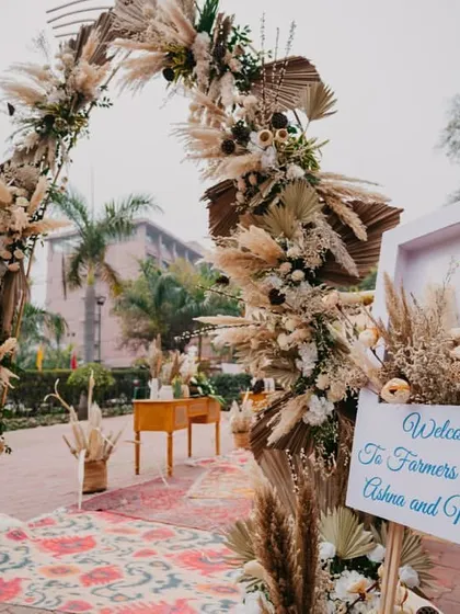 The entrance to a 'Farmer's Market' themed event, featuring a rustic arch of pampas grass and dried palms. This unique theme was a nod to the couple's story.