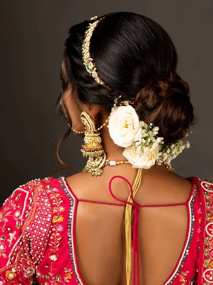 A detail shot of the bridal hairstyle, featuring a beautiful bun adorned with flowers and a traditional matha patti.