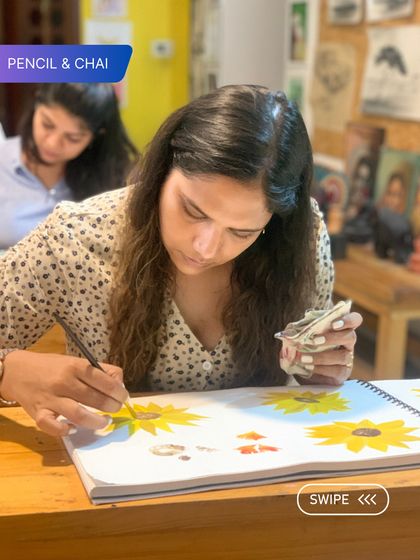 A student paints bright yellow sunflowers in her sketchbook. Our adult art classes are a space for discovery, where learners can explore subjects that bring them joy.