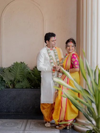 A beautifully composed portrait of the couple standing by a pillar, showcasing their traditional Maharashtrian wedding attire.