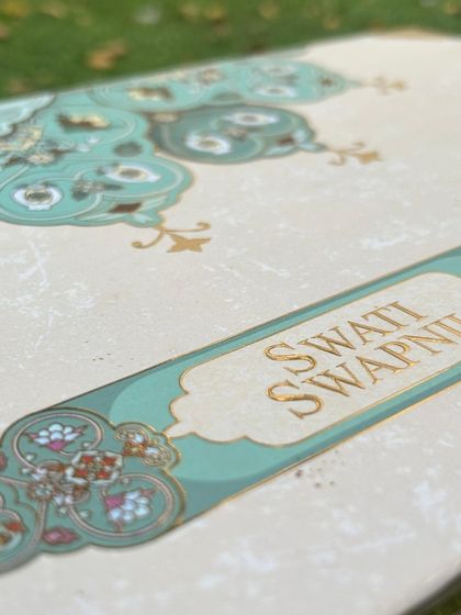 The beauty of this sea-green briefcase box is in its fine details. This close-up shows the elegant gold foil names and the intricate patterns that frame the nameplate, giving it a luxurious and bespoke feel.
