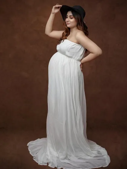 Adding a little flair with a stylish hat. This portrait in a simple white gown against a brown backdrop shows how a single prop can change the vibe of a photo.