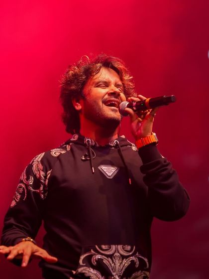 Javed Ali singing under intense red lighting, a testament to our dynamic and responsive lighting design during concerts.