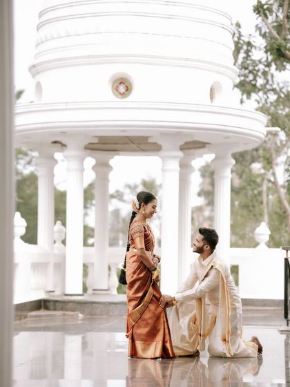 A truly romantic gesture as the groom gets on one knee before his bride. This shot, set against a grand white gazebo, is perfect for telling a fairytale love story.