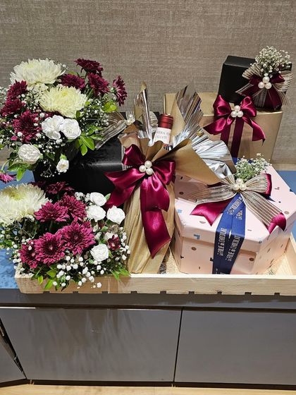 This large tray hamper was part of a corporate order for Shoppers Stop and Axis Bank. It includes a bottle of wine, gourmet food boxes, and a generous bouquet of fresh chrysanthemums, creating an impressive and abundant gift.