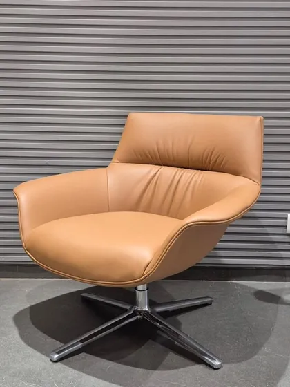 An angled view of the tan swivel lounge chair, showing its inviting and ergonomic shape.
