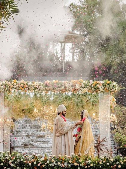 The couple exchanging garlands amidst rain and smoke, a truly cinematic wedding moment.