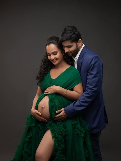 A beautiful couple's portrait in our emerald green gown. His hand gently rests on her bump, a simple gesture full of love and support.