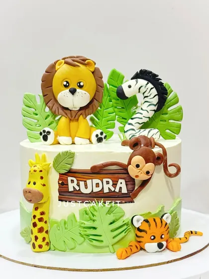 A jungle theme cake with all edible, hand-molded animals. The personalized wooden-style sign adds a rustic touch to this cute creation.