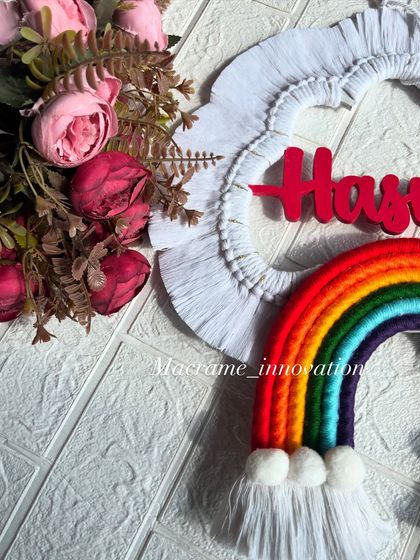A close-up shot of a vibrant rainbow name hanging for Hasrat, showing the texture of the cloud frame and the bright colors of the rainbow.