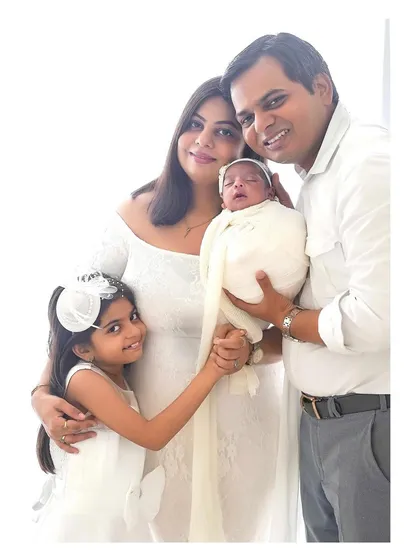 A timeless family portrait celebrating a new arrival. Dressed in classic white, this family's love shines through, creating an elegant and heartwarming image perfect for displaying in your home.