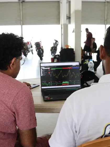 Two riders studying a laptop screen showing their track performance graphs. Understanding this data is the key to becoming a smarter, faster rider.