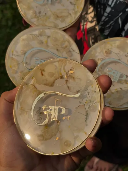 Another view of the custom logo coasters, showing the clear resin and the delicate placement of the flowers and gold flakes.