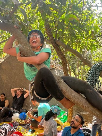 A climber having a laugh while hanging out in a tree between climbs. We always find time for fun and games at our workshops.