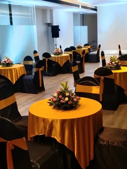 A chic seating arrangement for a corporate event or cocktail party. We used round tables with yellow tablecloths and chairs covered in black with gold sashes, each with a simple floral centerpiece.