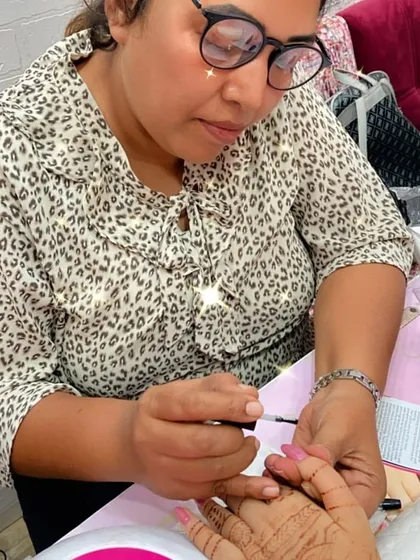 A student applies a base coat to a client's nails, a crucial step for a long-lasting and healthy manicure.
