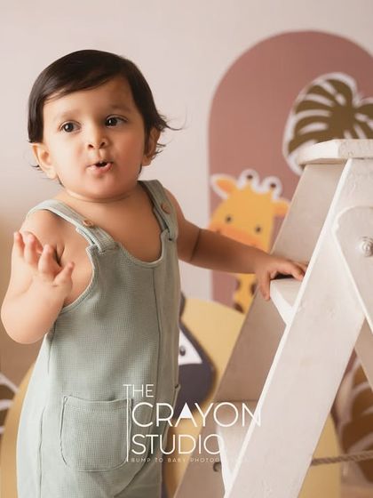 A little boy with a curious expression during his jungle-themed first birthday shoot. The cute animal cutouts create a playful safari atmosphere.