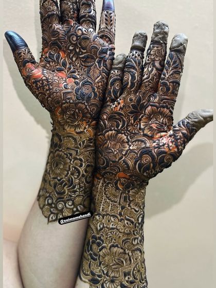The slight orange tint in this photo shows the henna paste as it begins to dry. The design itself is a beautiful, dense floral pattern.
