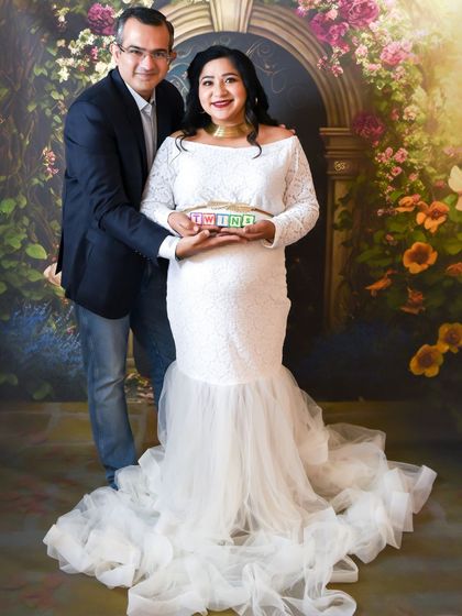 A joyful couple announcing they are expecting twins with cute letter blocks in our floral studio setup.