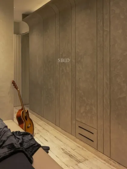 A detail shot of the teen's room, showing the curved grey stucco wall that houses the wardrobe. The clean lines and textured finish create a sophisticated yet cool vibe.
