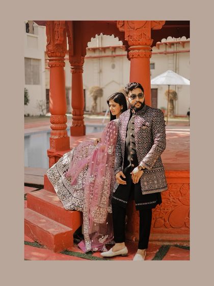 A stylish portrait of the couple posing on the steps of a red gazebo, their elaborate outfits creating a look of modern royalty.