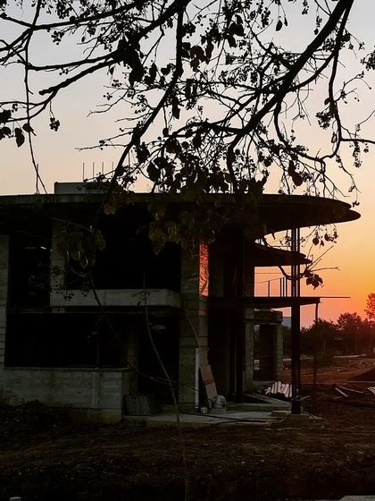 The silhouette of the Soma house at sunset, seen here during construction, captures a moment of 'Cardinal Silence'. The structure's form, with its distinctive floating roof, was designed to honor the quiet majesty of its surroundings.
